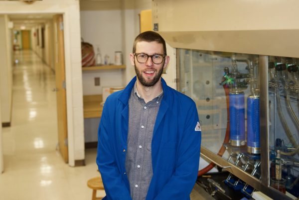 Christopher Bejger wears a blue lab coat in his lab.