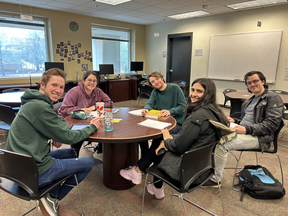 Five students sitting around a table studying math.